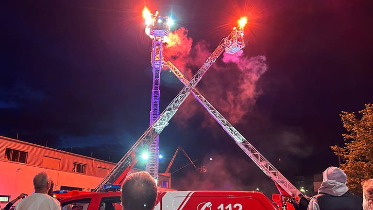 Brennende Fackeln tanzen auf ausgefahrenen Drehleitern bei der Nacht der offenen Tür der Feuerwehr Reutlingen.  (Foto: SWR, Tobias Faißt)